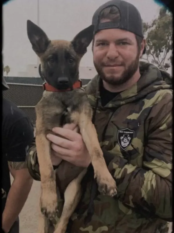 Patrick Mullooly, USMC veteran and head trainer at True North Canine, holding a Belgian Malinois puppy